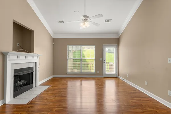 a view of an empty room with window and wooden floor