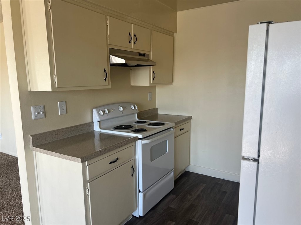 1388 East Desert Inn Road, Unit 1 Las Vegas, NV 89169 - Photo 2 of 17 Kitchen with white appliances, under cabinet range hood, baseboards, dark wood-type flooring, and dark countertops