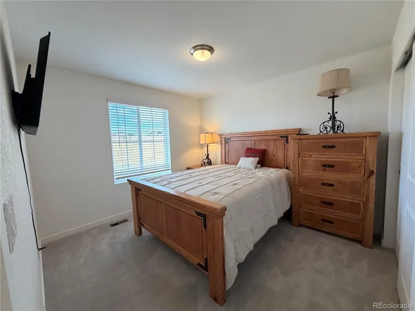 a bedroom with a bed and a flat tv screen on the dresser