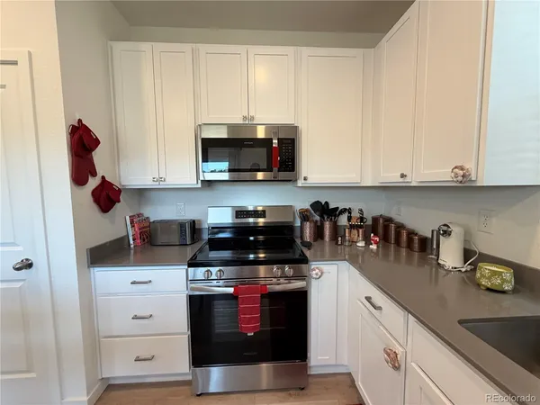 a kitchen with stainless steel appliances granite countertop white cabinets and a stove a sink