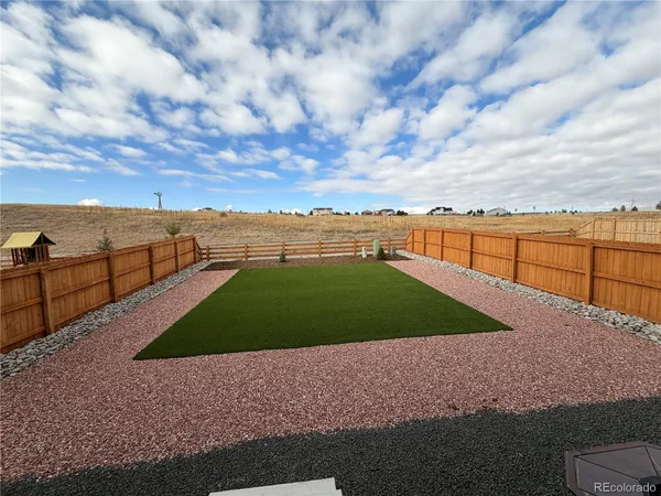a view of house with a big yard and large trees