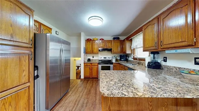 a kitchen with stainless steel appliances granite countertop a refrigerator stove and sink