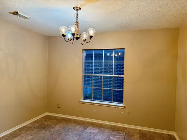 a view of an empty room with a window and chandelier fan