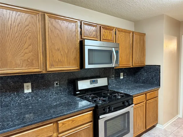 a kitchen with granite countertop cabinets stainless steel appliances and a counter space