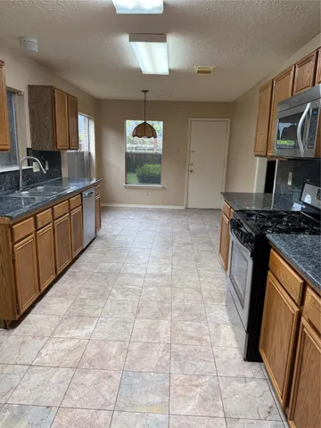 a kitchen with stainless steel appliances granite countertop a stove a sink and a microwave
