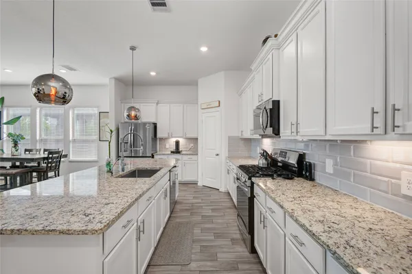 a large kitchen with granite countertop a large counter top and stainless steel appliances