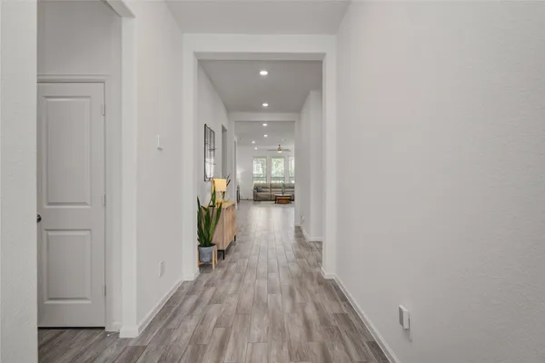 a view of a hallway with wooden floor and a living room