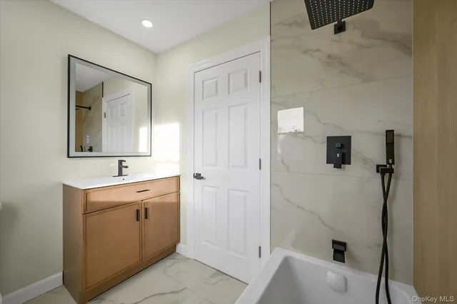 a bathroom with a bathtub sink and mirror