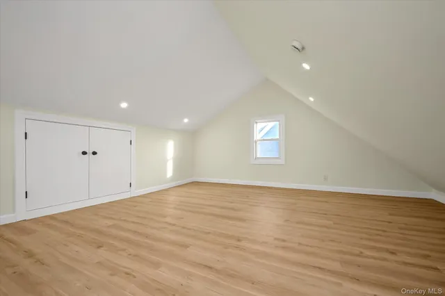 a view of an empty room with wooden floor and window