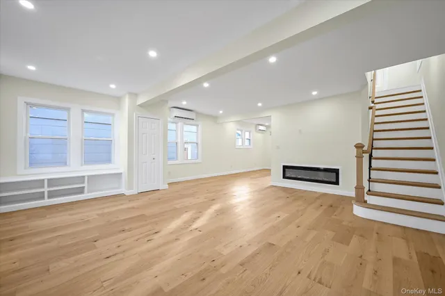 a view of an empty room with wooden floor and windows