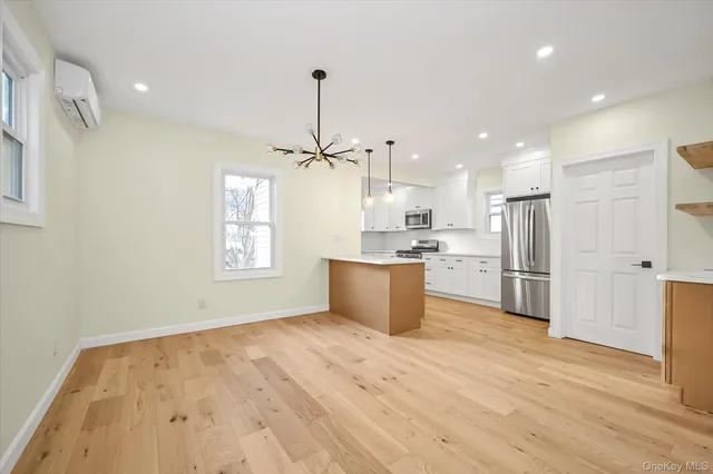 a large kitchen with a refrigerator a sink dishwasher a stove and white cabinets with wooden floor