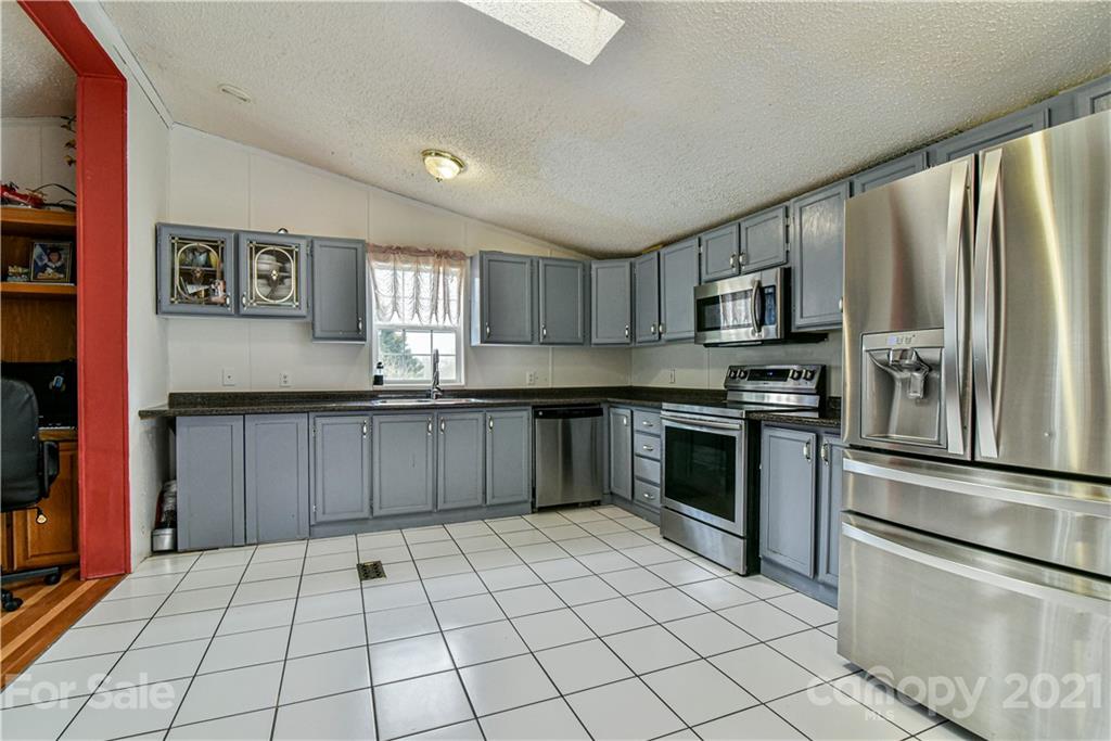 599 Pace Road Hendersonville, NC 28792 - Photo 5 of 24 a kitchen with granite countertop a refrigerator and a stove top oven