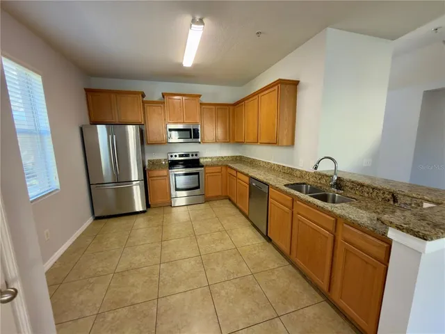 a large kitchen with stainless steel appliances granite countertop a sink stove and refrigerator
