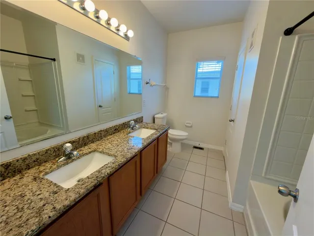 a bathroom with a granite countertop sink a mirror and a bathtub