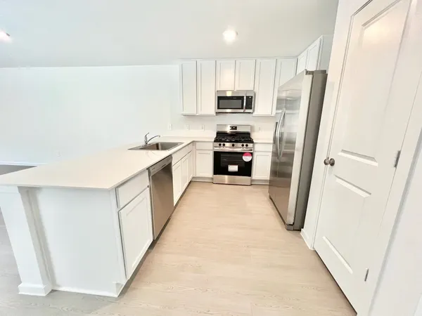 a kitchen with white cabinets and refrigerator