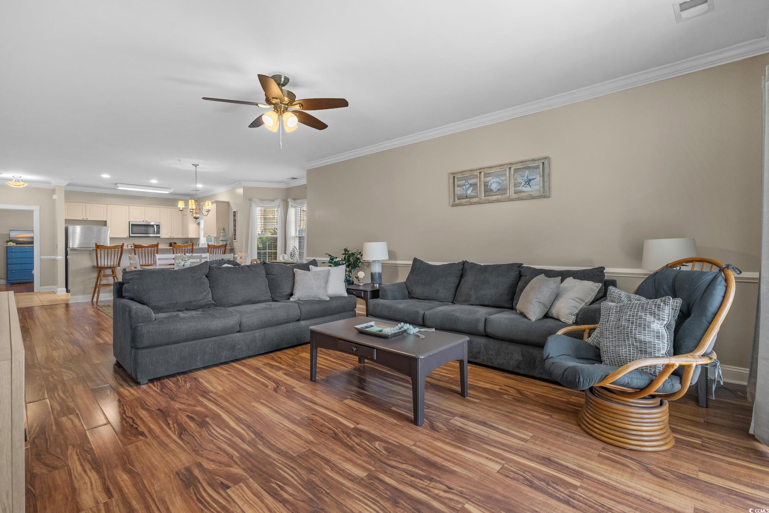4823 Magnolia Lake Drive, Unit 101 Myrtle Beach, SC 29577 - Photo 10 of 35 Living room with crown molding, wood finished floors, ceiling fan, and a chandelier