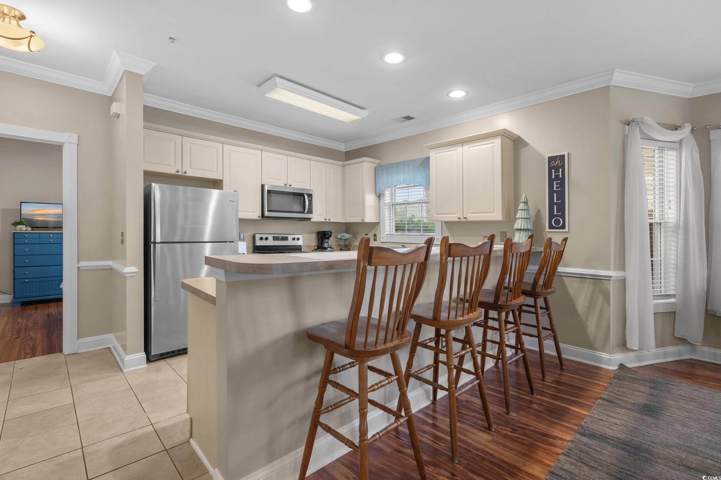 4823 Magnolia Lake Drive, Unit 101 Myrtle Beach, SC 29577 - Photo 12 of 35 Kitchen featuring stainless steel appliances, a kitchen bar, crown molding, recessed lighting, and light countertops