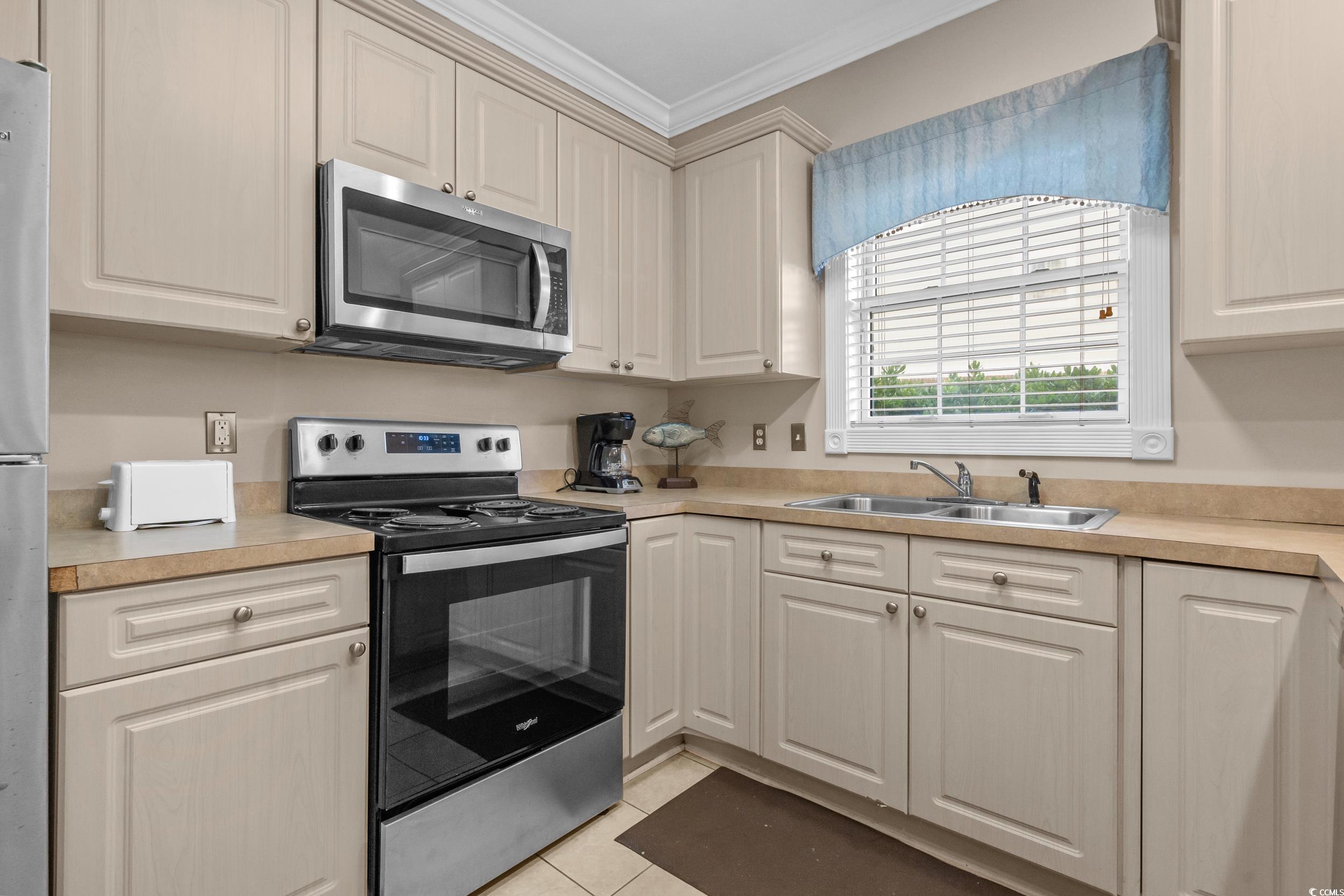 4823 Magnolia Lake Drive, Unit 101 Myrtle Beach, SC 29577 - Photo 13 of 35 Kitchen with stainless steel appliances, light countertops, light tile patterned floors, and ornamental molding