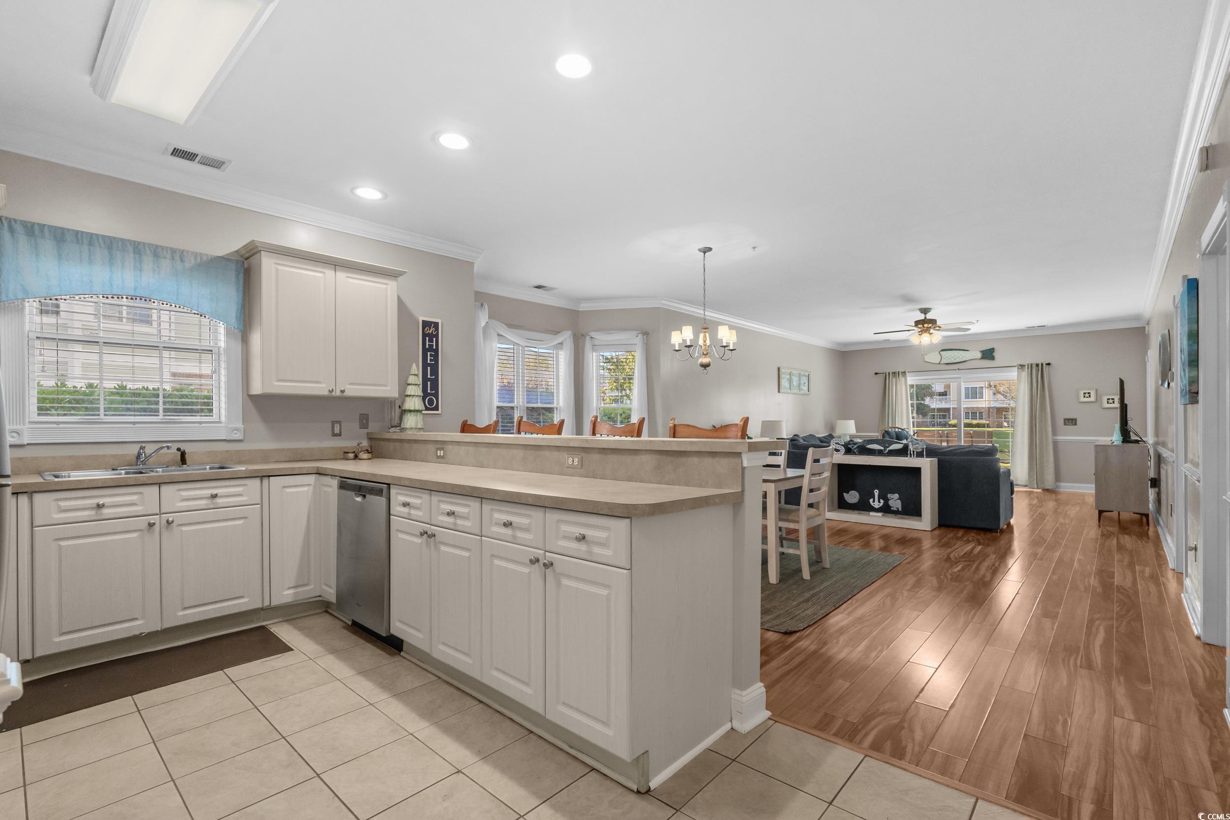 4823 Magnolia Lake Drive, Unit 101 Myrtle Beach, SC 29577 - Photo 33 of 35 Kitchen with crown molding, hanging light fixtures, a chandelier, a peninsula, and open floor plan