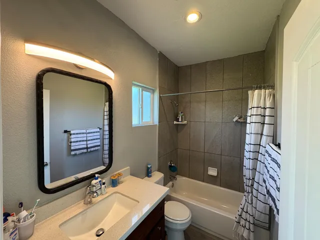 a bathroom with a sink a toilet and shower a mirror