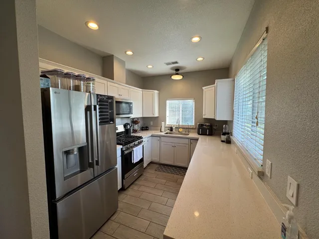 a kitchen with stainless steel appliances granite countertop a refrigerator a sink dishwasher a stove and a refrigerator