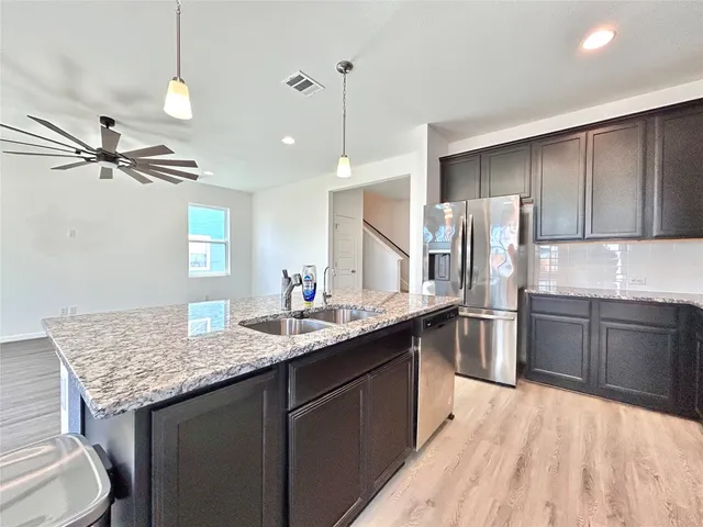 a kitchen with stainless steel appliances granite countertop a sink refrigerator and cabinets