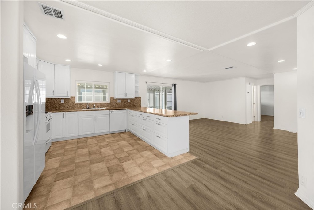 10210 Base Line Road, Unit 291 Rancho Cucamonga, CA 91701 - Photo 13 of 27 a large white kitchen with wooden floors and stainless steel appliances