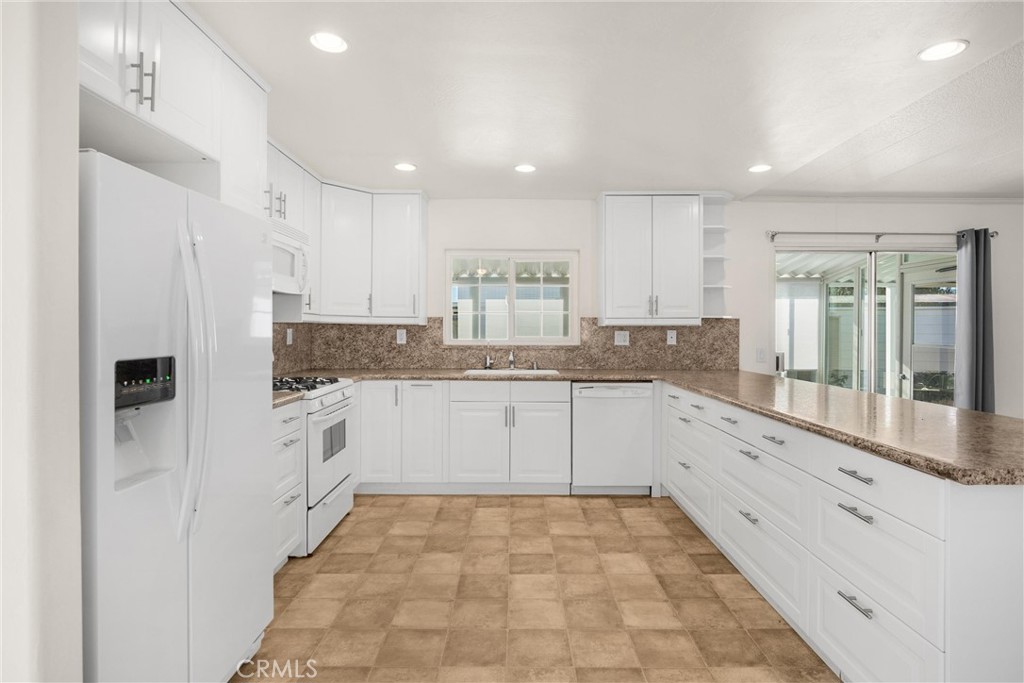 10210 Base Line Road, Unit 291 Rancho Cucamonga, CA 91701 - Photo 14 of 27 a large kitchen with granite countertop a stove a sink dishwasher a refrigerator and white cabinets with wooden floor