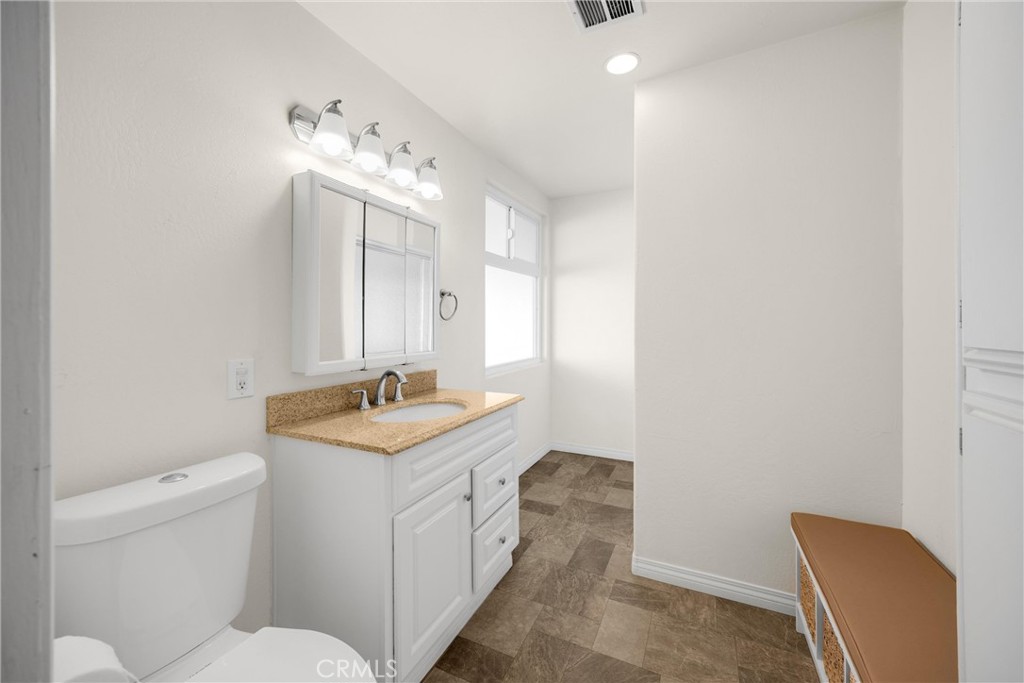 10210 Base Line Road, Unit 291 Rancho Cucamonga, CA 91701 - Photo 19 of 27 a bathroom with a granite countertop sink a toilet and a mirror