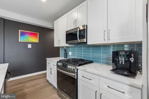 a view of living room kitchen with stainless steel appliances granite countertop a sink and a large window