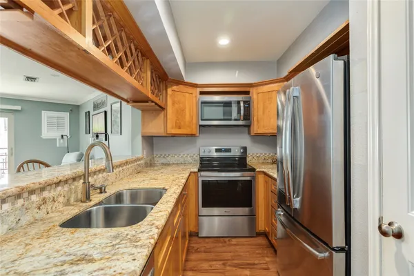 a kitchen with stainless steel appliances granite countertop a refrigerator a sink a stove a washer dryer and a refrigerator