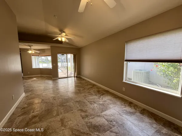 a view of empty room with window and ceiling fan