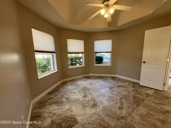 en empty room with windows and ceiling fan