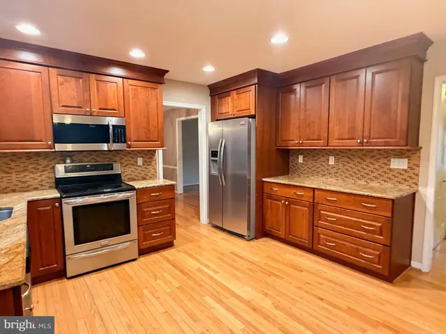 a kitchen with stainless steel appliances granite countertop a stove a refrigerator and a microwave oven