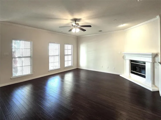 a view of an empty room with wooden floor fireplace and a window