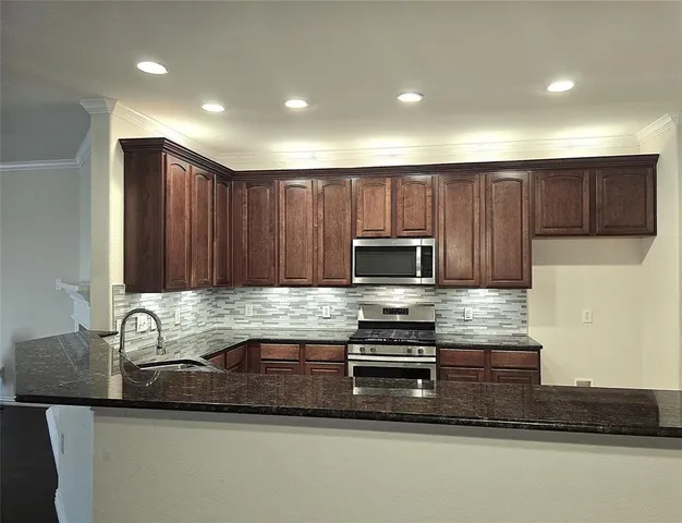 a kitchen with granite countertop a stove sink and microwave
