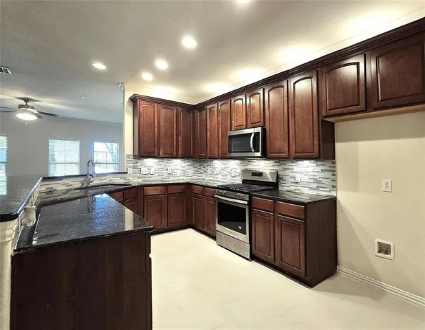 a kitchen with granite countertop wooden cabinets and stainless steel appliances