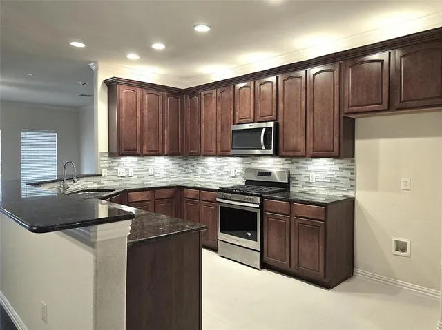 a kitchen with kitchen island granite countertop stainless steel appliances a stove a sink a refrigerator and cabinets