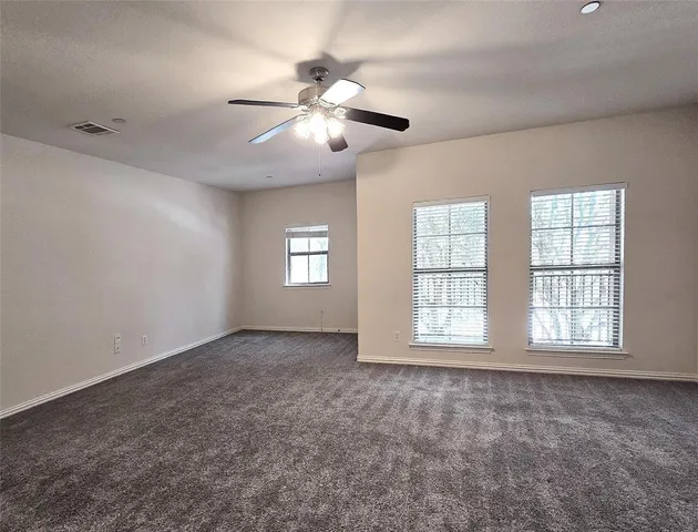 an empty room with windows and fan chandelier