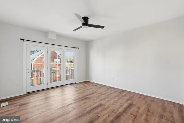 an empty room with wooden floor fan and windows