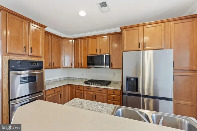 a kitchen with granite countertop a refrigerator and a stove top oven