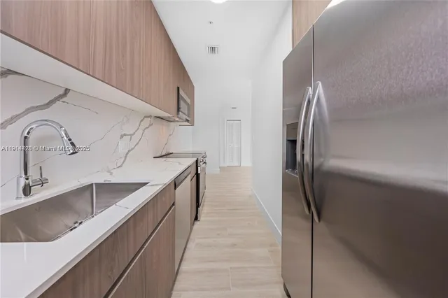 a kitchen with kitchen island granite countertop a sink and refrigerator