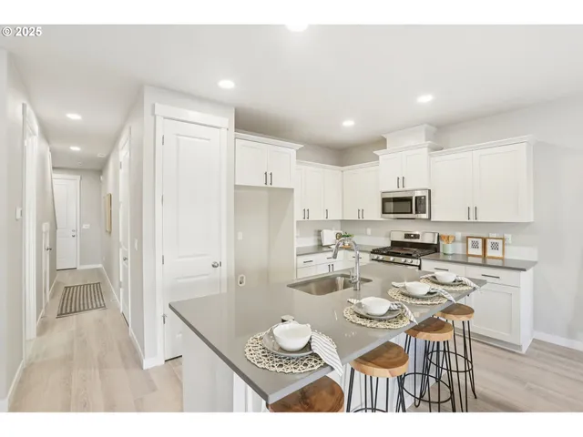 a kitchen with stainless steel appliances a dining table chairs stove refrigerator and cabinets