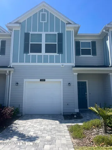 a view of a house with a small yard and wooden fence