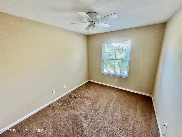 an empty room with a window and a ceiling fan