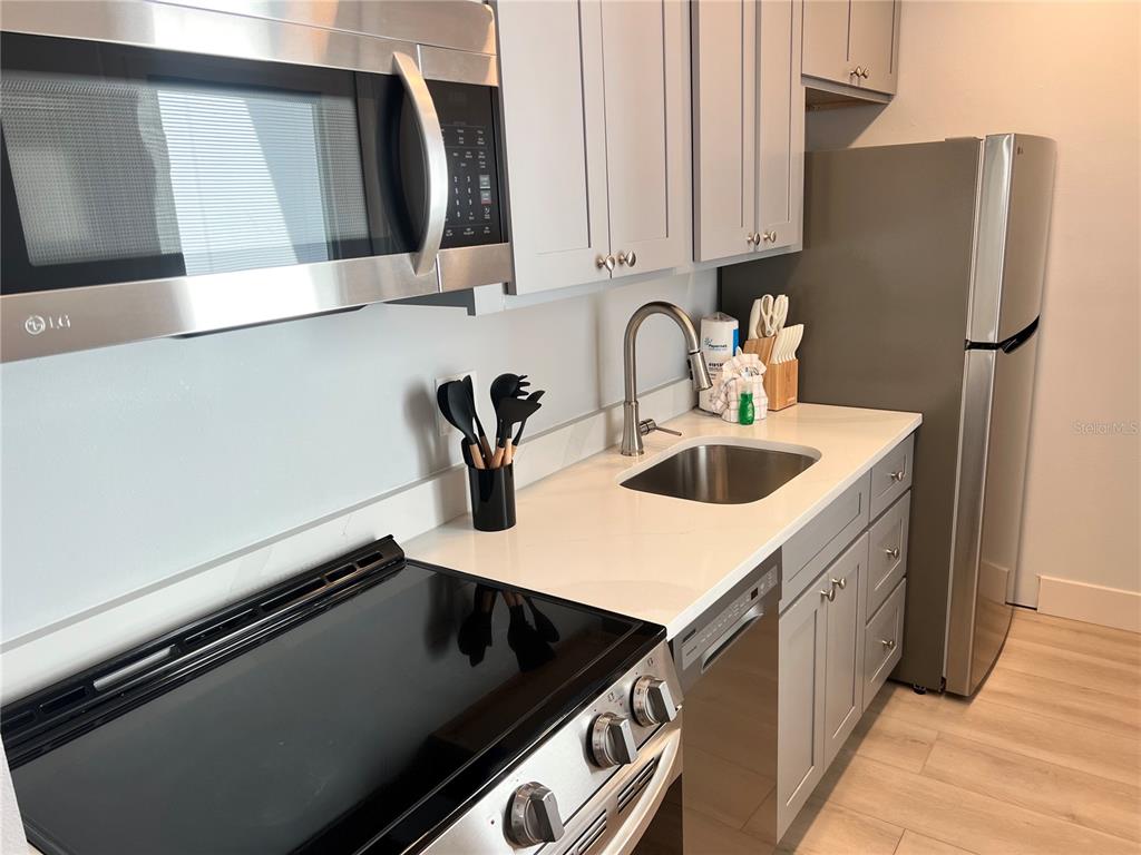 6020 Midnight Pass Road, Unit 32 Sarasota, FL 34242 - Photo 7 of 13 a kitchen with stainless steel appliances a sink and a refrigerator