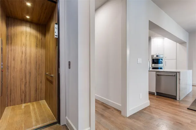 a view of a hallway with kitchen and wooden floor