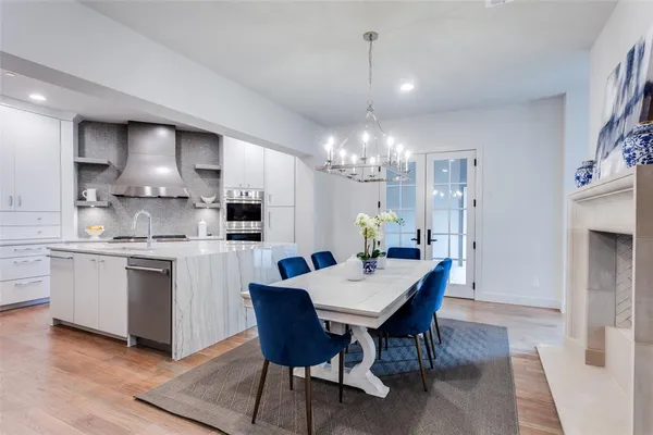 a kitchen with stainless steel appliances kitchen island granite countertop a table chairs and a refrigerator