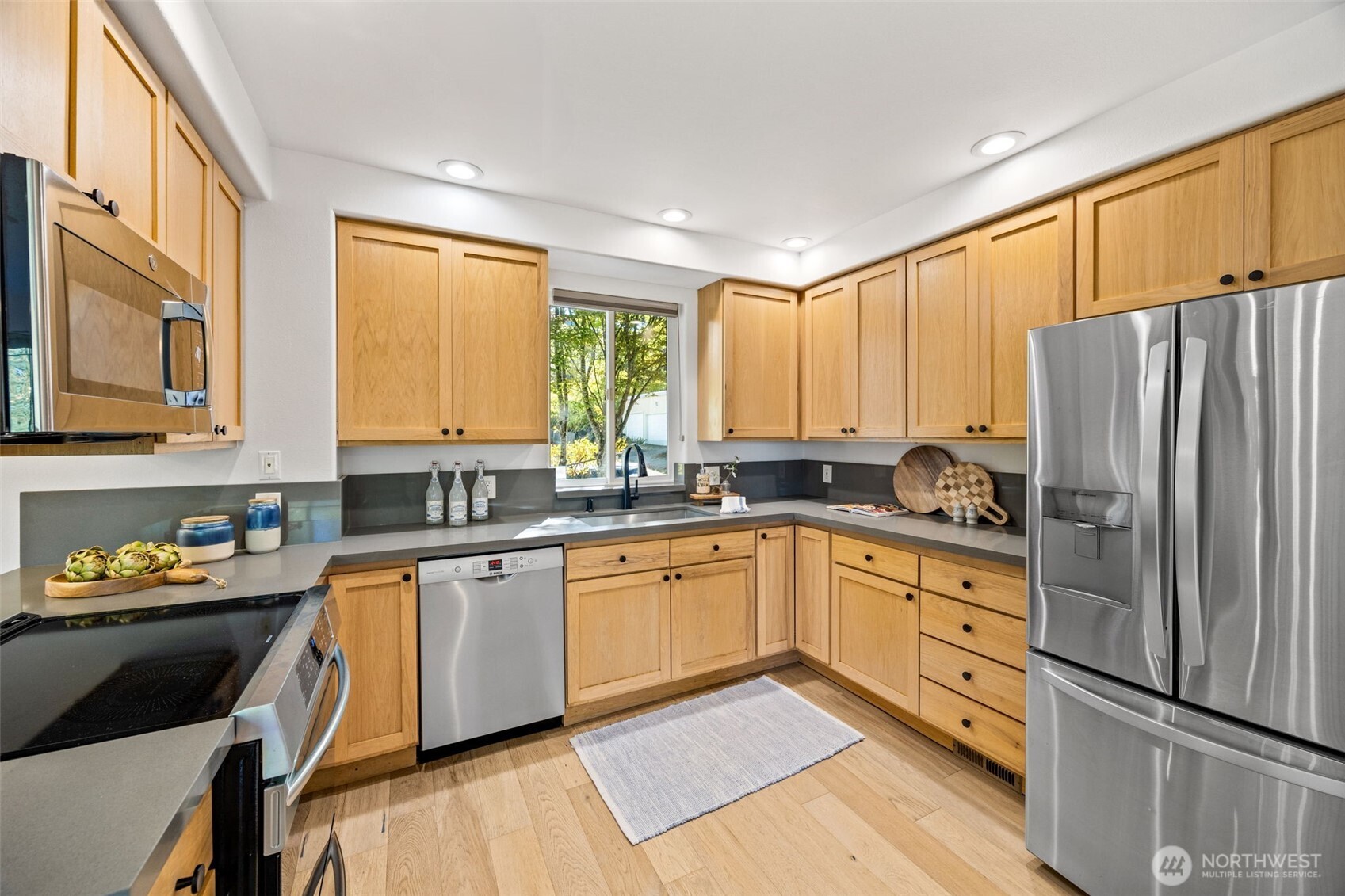 2613 East Howell Street Seattle, WA 98122 - Photo 7 of 31 a kitchen with stainless steel appliances granite countertop a refrigerator a sink dishwasher a stove and white countertops with wooden floor