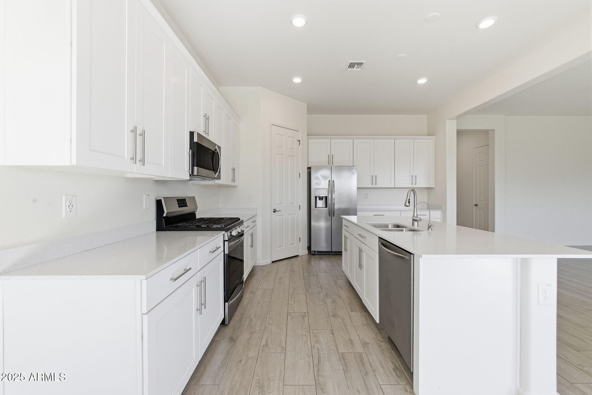 18545 West Chuckwalla Canyon Road Goodyear, AZ 85338 - Photo 5 of 26 a kitchen with stainless steel appliances a sink stove top oven and white cabinets